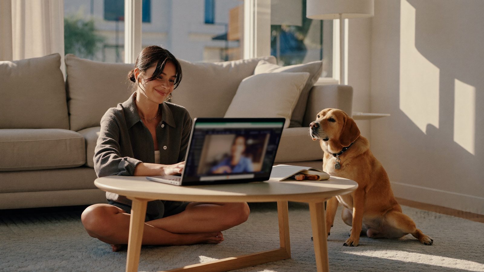 Dog owner in a virtual dog training session on a laptop with her dog beside her